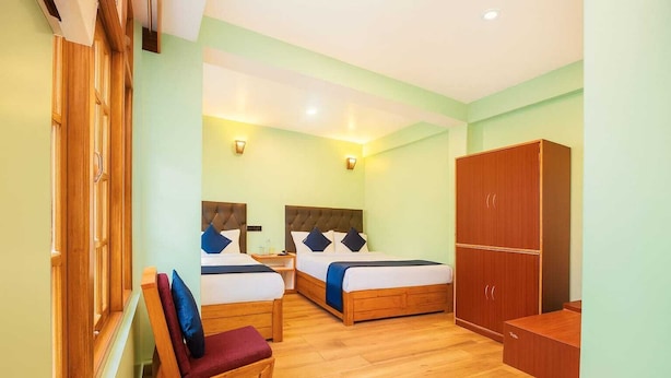 Une chambre d’hôtel avec deux lits, des meubles en bois et une armoire.