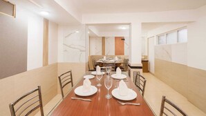 Un vaste espace dédié à la salle à manger, avec une longue table en bois dressée pour le repas, entourée de chaises.