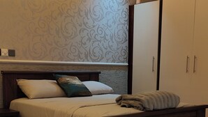 Een slaapkamer met een bed, nachtkastje, kledingkast en een plafondventilator.