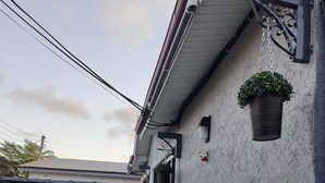 Een woongebouw met een auto op de oprit, bloempotten en een heldere lucht.