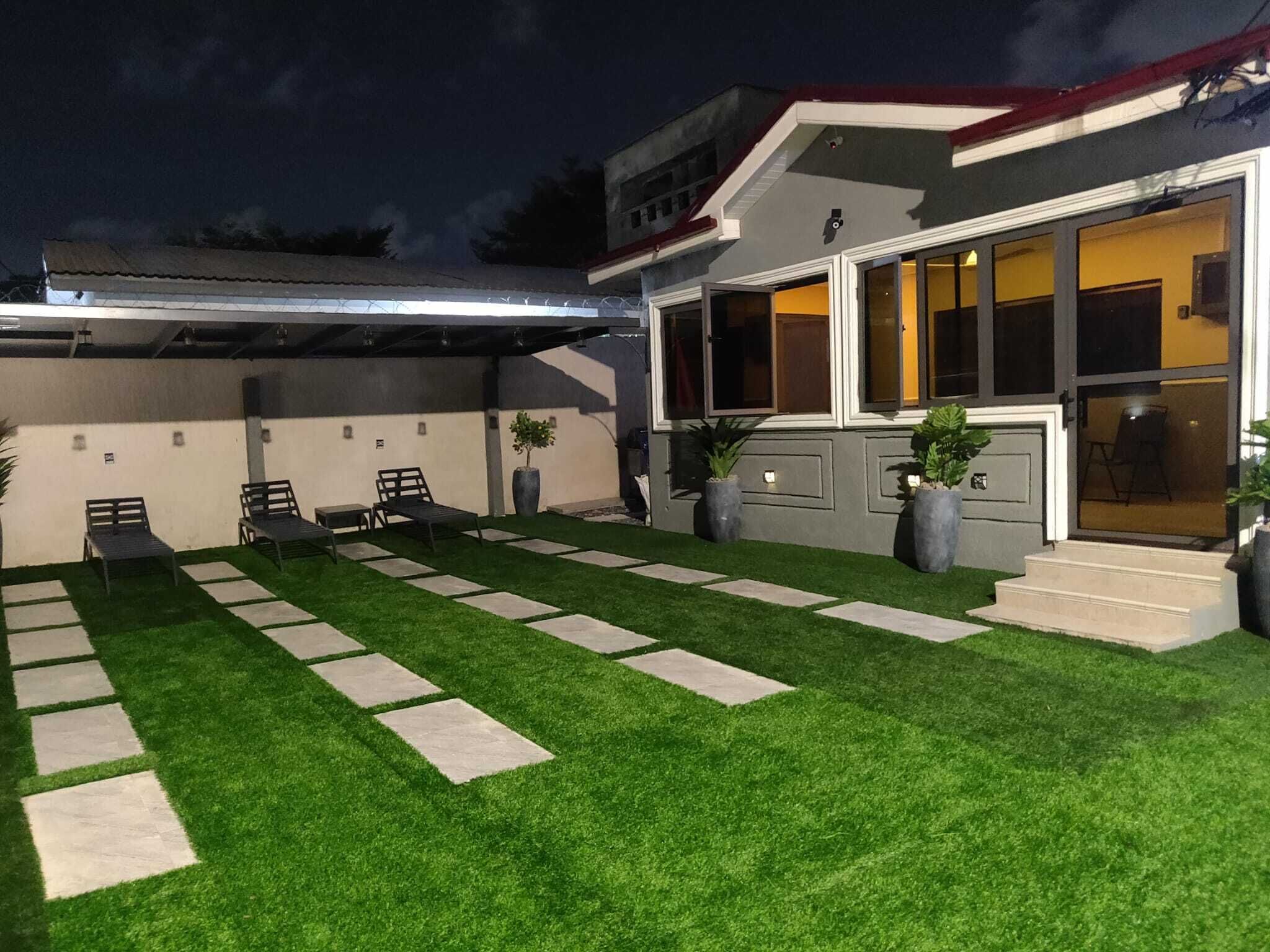 A modern house with a well-maintained lawn, outdoor seating area, and large windows.