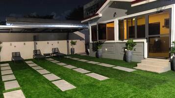 A modern house with a well-maintained lawn, outdoor seating area, and large windows.