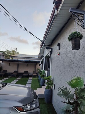 A modern house with a car parked in the driveway, a well-maintained lawn, and several potted plants. - Ghanastays a very modern and stylish House with all the amenities to relax. (Tema)