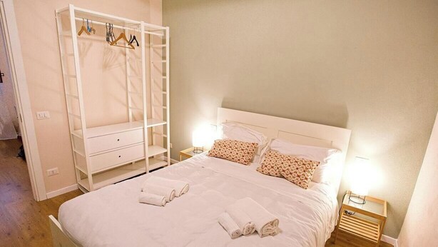 A neatly made bed with rolled towels, a white wardrobe with hangers, and a bedside table with a lamp. - CASA AL GELSO, authentic Tuscan atmosphere (Lucca)