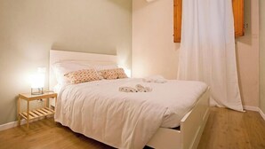 A neatly made bed with white linens, a bedside table with a lamp, and a wooden floor. - CASA AL GELSO, authentic Tuscan atmosphere (Lucca)