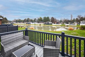 A deck with wicker furniture overlooking a lake, surrounded by mobile homes. - Host Stay Mulberry Lodge (York)