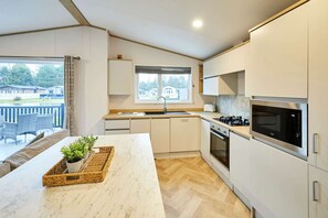 A modern kitchen with white cabinets, a marble countertop, and a built-in oven. - Host Stay Mulberry Lodge (York)