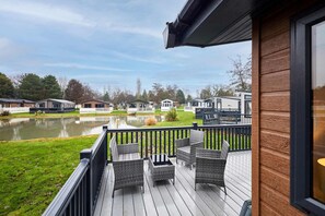 A deck with wicker furniture overlooking a lake, surrounded by mobile homes. - Host Stay Mulberry Lodge (York)