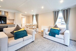 A modern living room with two sofas, a dining table, and a kitchen area. - Host Stay Dakota Lodge (York)