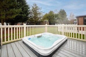 A hot tub on a wooden deck with a white fence and trees in the background. - Host Stay Dakota Lodge (York)
