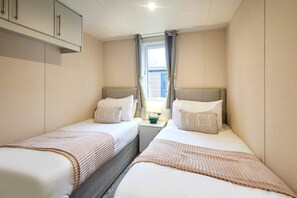 A compact bedroom with two beds, a small window, and a cabinet above the beds. - Host Stay Dakota Lodge (York)