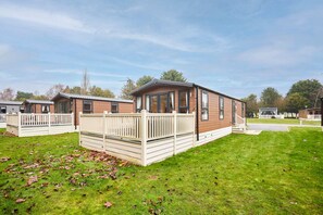 A row of mobile homes with a grassy lawn and white fences. - Host Stay Dakota Lodge (York)