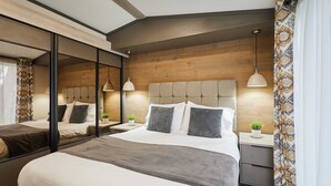 Un dormitorio moderno con una cama grande, mesitas de noche, un espejo y un cabecero de madera.