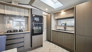 Una cocina moderna con electrodomésticos integrados, un tragaluz y una ventana con persianas.