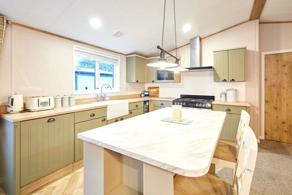 A modern kitchen with green cabinets, a large island, and a window providing natural light. - Host Stay Peace Lodge (York)