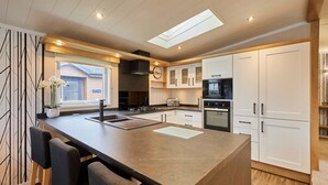 A modern kitchen with a central island, built-in appliances, and a skylight. - Host Stay Four Seasons Lodge (York)