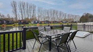 A deck with a table and chairs overlooking a pond and row of houses. - Host Stay Four Seasons Lodge (York)
