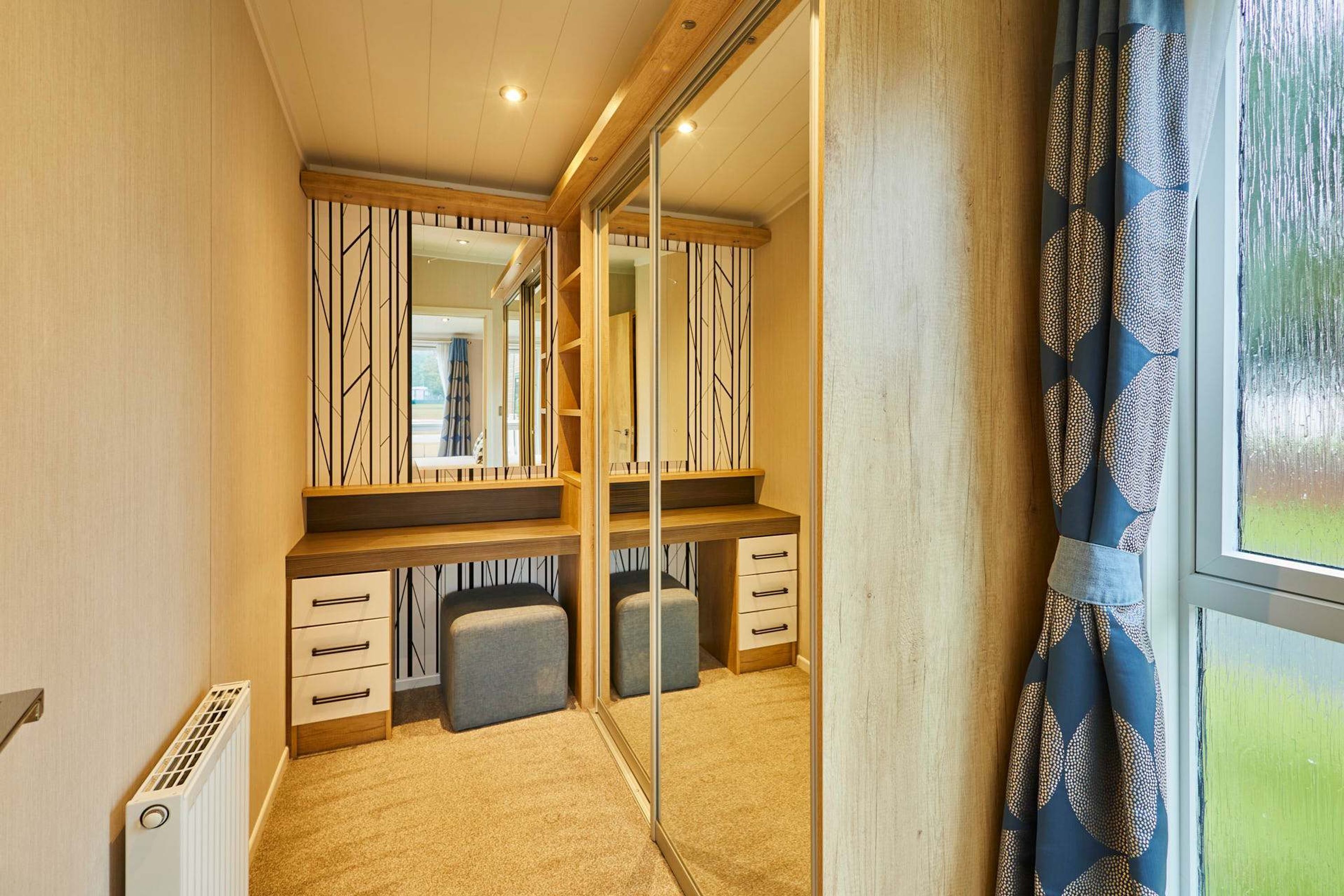 A compact bedroom with a mirrored wardrobe, a bedside table, and a single bed.