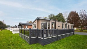 A mobile home with a fenced deck, large windows, and a flat roof. - Host Stay Four Seasons Lodge (York)