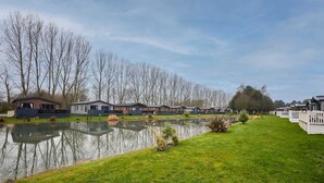 A row of modern, single-story houses with a small pond in the foreground. - Host Stay Four Seasons Lodge (York)