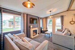 A cozy living room with a fireplace, two sofas, a coffee table, and large windows with curtains. - Host Stay Oakwood Lodge (York)