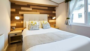 Ein ordentlich eingerichtetes Schlafzimmer mit einem großen Bett, zwei Nachttischen und einem Holzkopfstück.