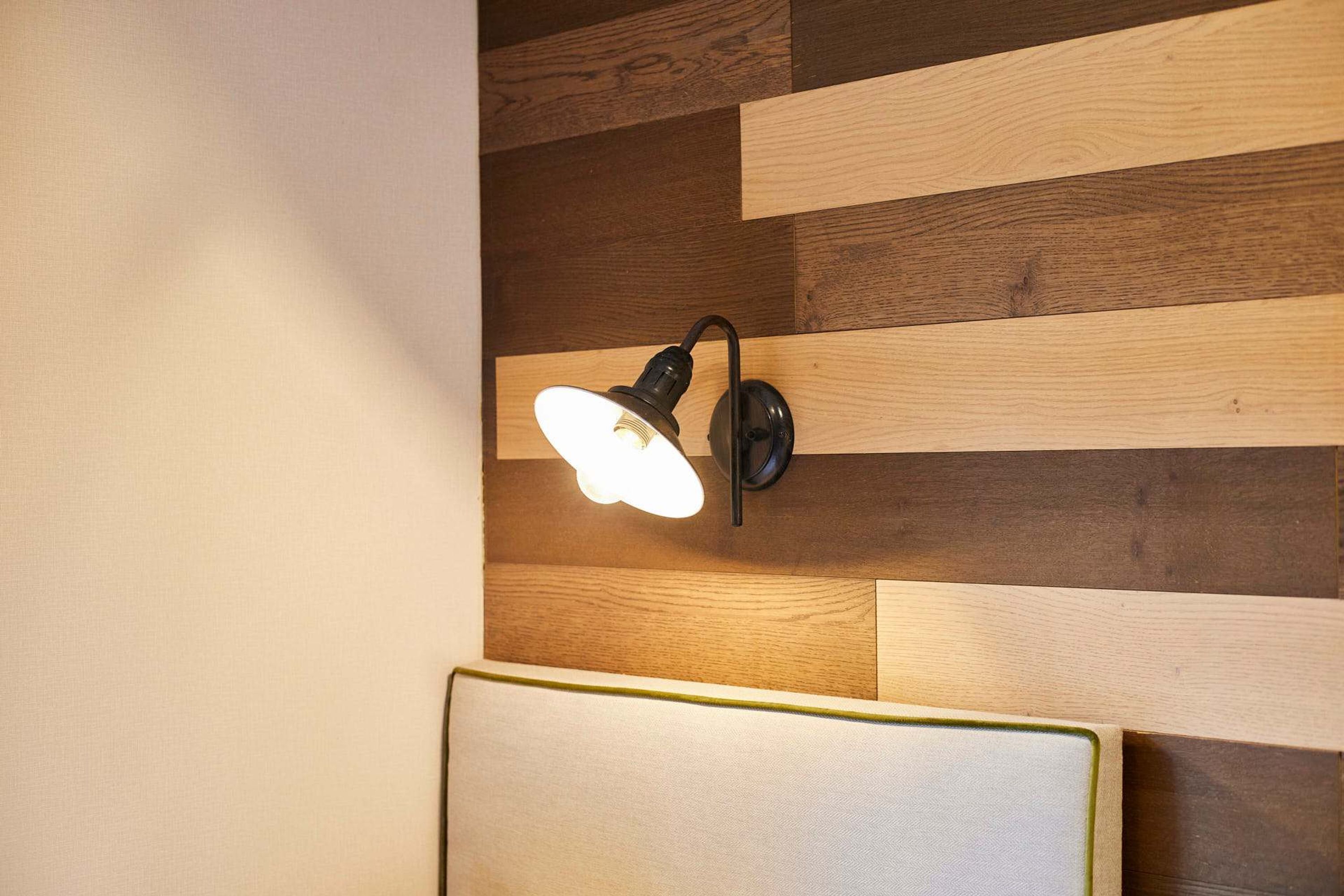 Un mur orné d’un panneau en bois et doté d’un luminaire fixé au mur.