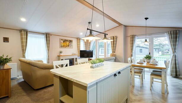 Ein gemütliches Wohnzimmer mit einer Couch, einem Esstisch mit Stühlen, einer Kücheninsel und einem Fernseher.
