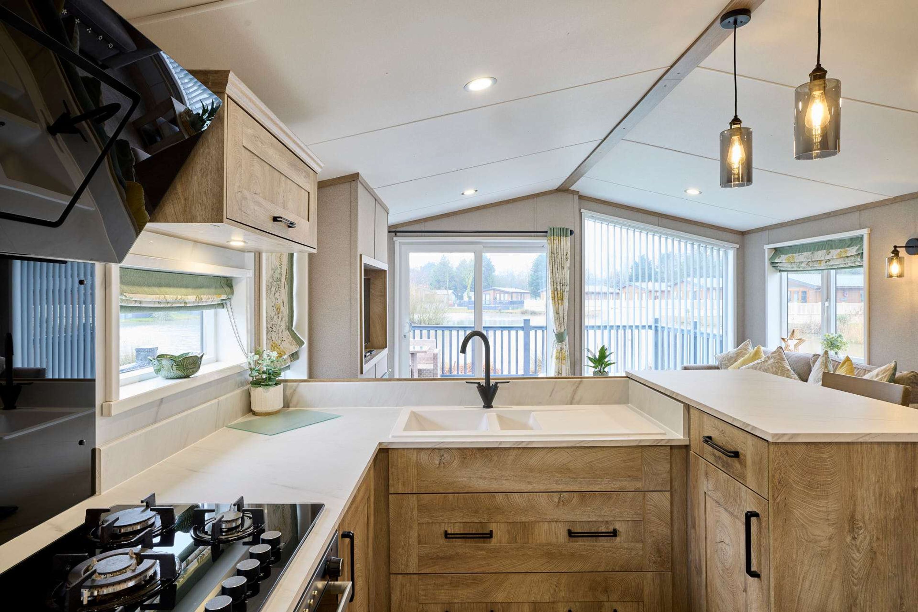 Una cocina moderna con armarios de madera, una estufa empotrada y un amplio ventanal con vistas al exterior.