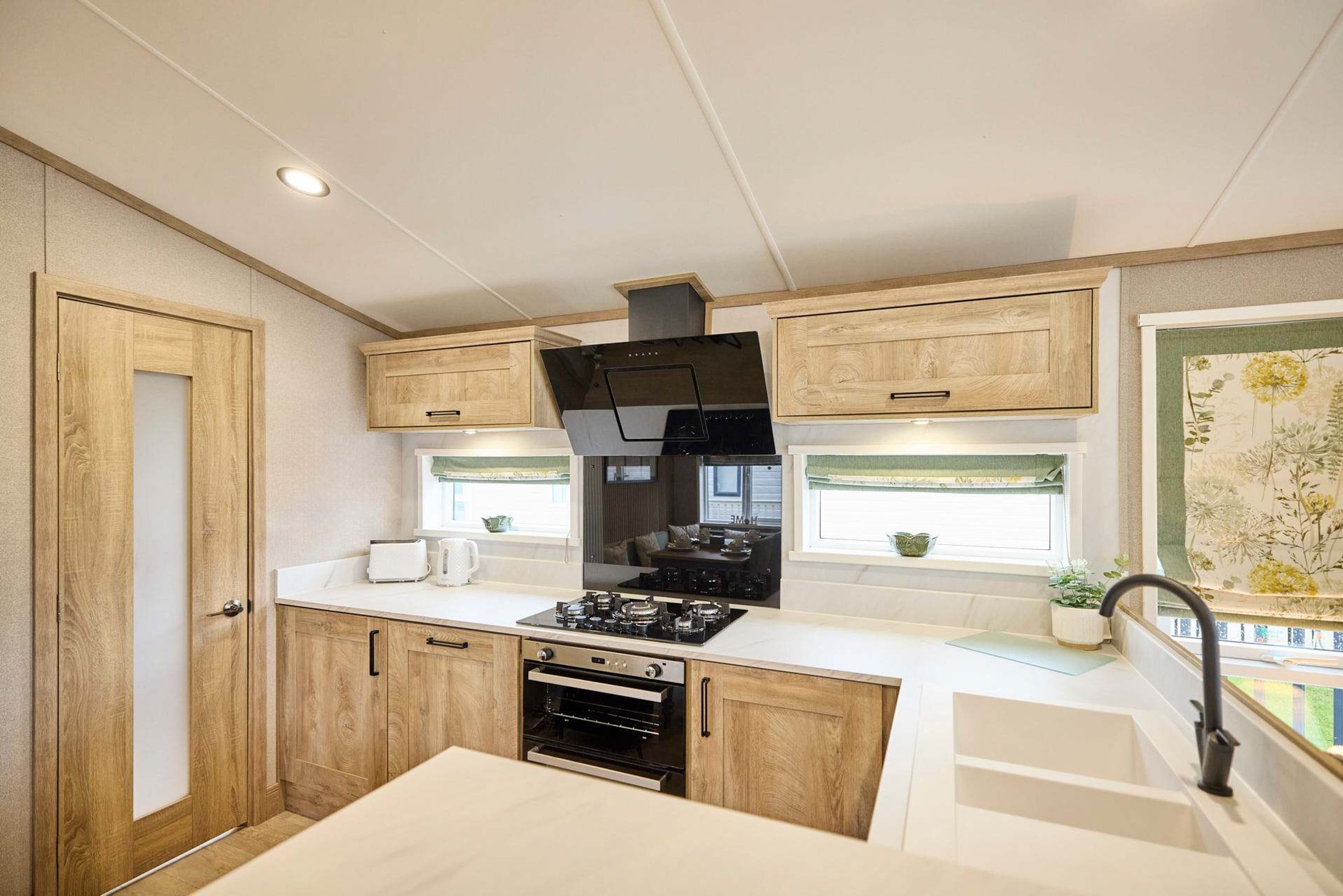 A compact kitchen with wooden cabinets, a stove, oven, and a window with a view.