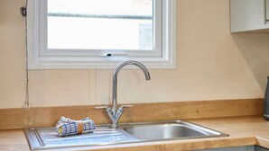 A kitchen with a stainless steel sink, a window above the sink, and a towel on the counter. - Host Stay Fairview Lodge (York)