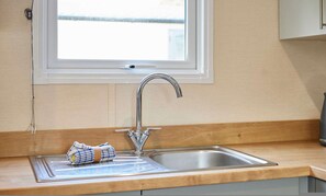 A kitchen with a stainless steel sink, a window above the sink, and a towel on the counter. - Host Stay Fairview Lodge (York)