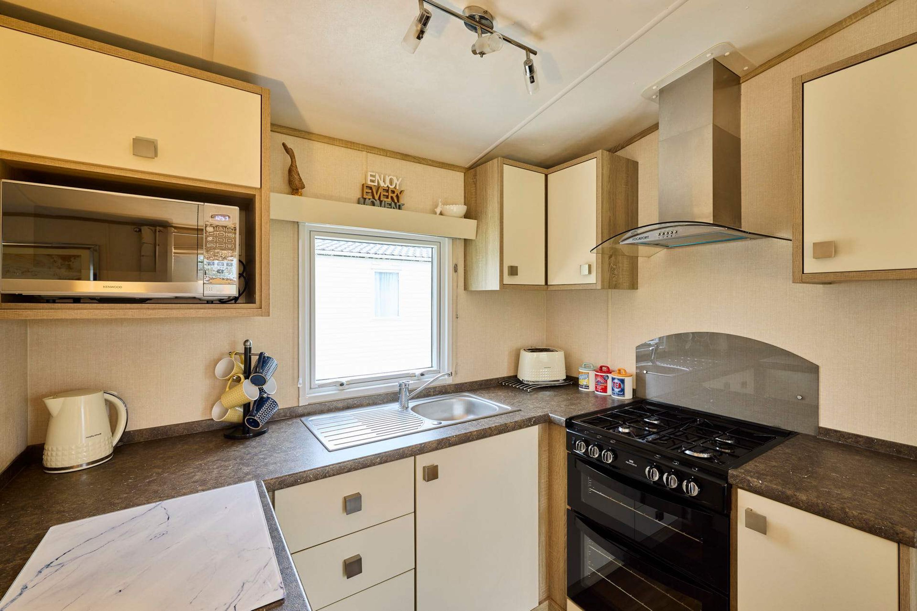A compact kitchen with a built-in microwave, a stove, and a sink.