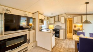 A compact kitchen with a TV, stove, and dining area. - Host Stay The Major Oak Lodge (York)