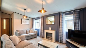 A living room with a sofa, a coffee table, a fireplace, a television, and a mirror. - Host Stay Truemans Lodge (York)