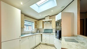 A modern kitchen with a skylight, built-in appliances, and a herringbone floor pattern. - Host Stay Truemans Lodge (York)
