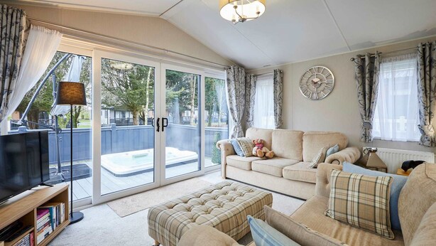 Ein gemütliches Wohnzimmer mit Sofa, Hocker und Fernseher auf einem Schrank.