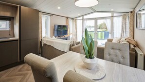 A modern, well-lit room with a dining table, chairs, a potted plant, and a television. - Host Stay The Kestrel Lodge (York)