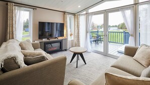 A cozy living room with a flat-screen TV, comfortable sofas, and a small table. - Host Stay The Kestrel Lodge (York)