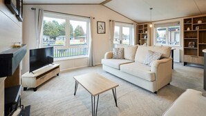 Een moderne woonkamer met een bank, een televisie, een salontafel en een open haard.
