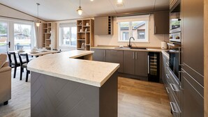 Een moderne keuken met een centraal eiland, inbouwplanken en een groot raam.