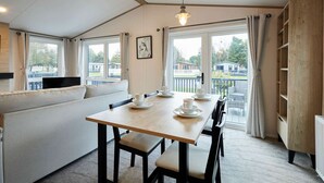 Een gezellig eetgedeelte met een houten tafel gedekt voor vier personen, een bank en uitzicht op het balkon.