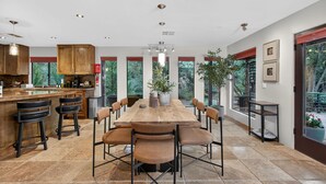 Een ruime keuken met een grote houten tafel, barstoelen en een vast kookeiland.