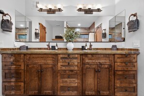 Une coiffeuse en bois avec un grand miroir, un vase rempli de fleurs et un distributeur de savon.