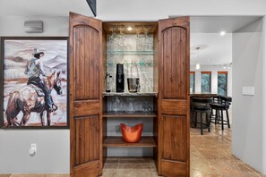 A kitchen with wooden cabinets, a glass shelf with wine glasses, and a painting of a cowboy on a horse. - NEW Luxe Chapel Garden Retreat Chapel Views (Sedona)