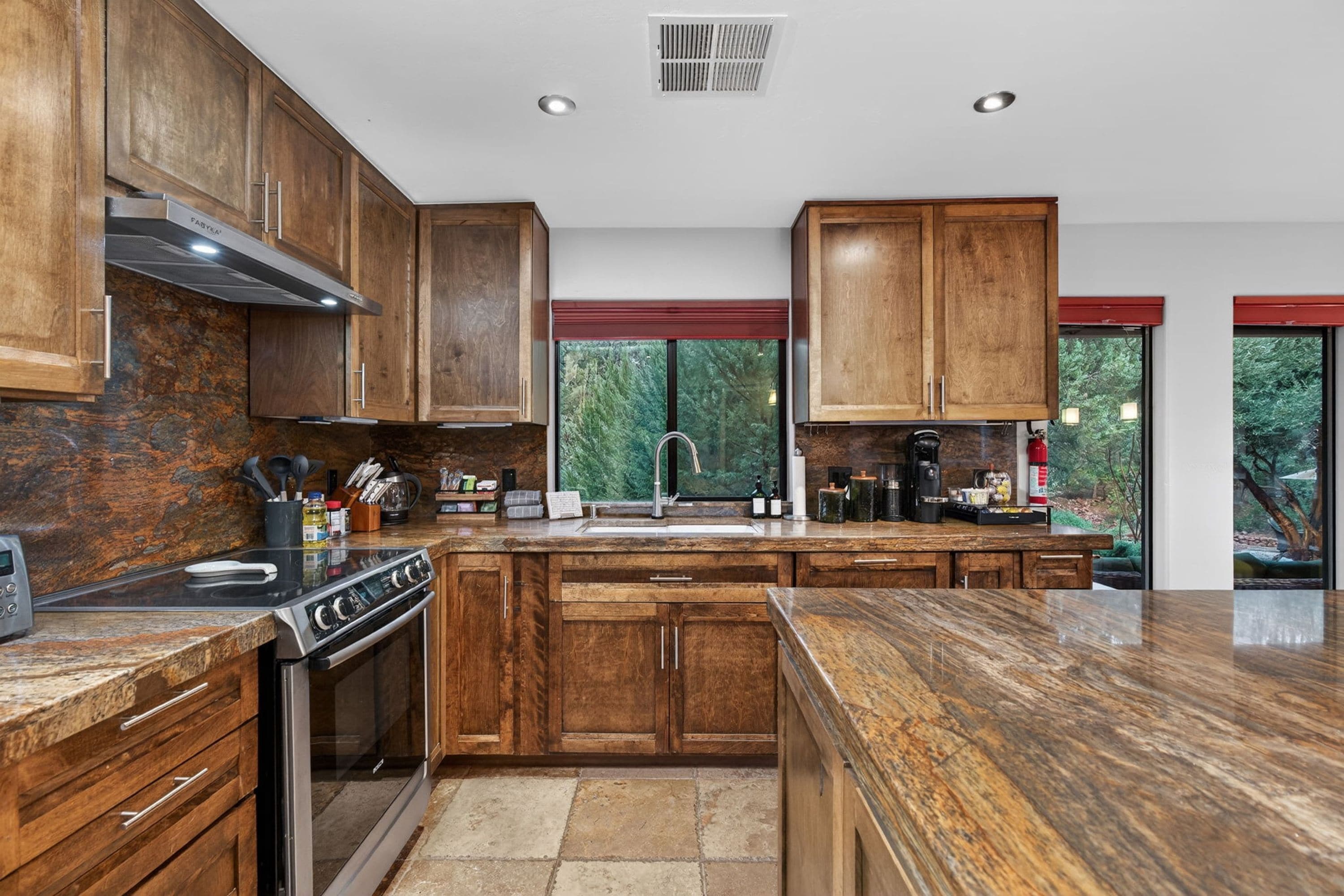Une cuisine moderne avec des meubles en bois, une cuisinière en acier inoxydable et un plan de travail en granit.