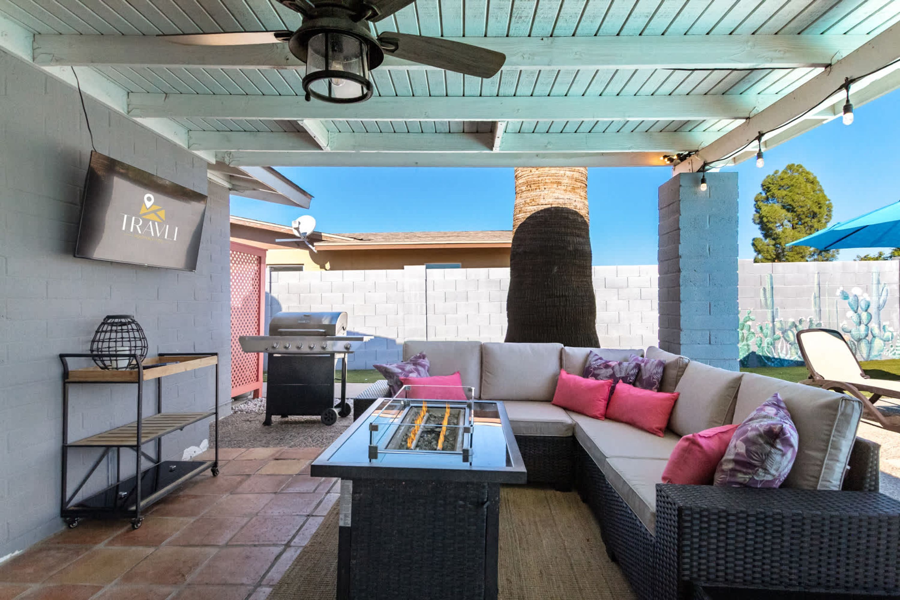 Une terrasse extérieure avec un canapé d’angle, un barbecue et un ventilateur de plafond.