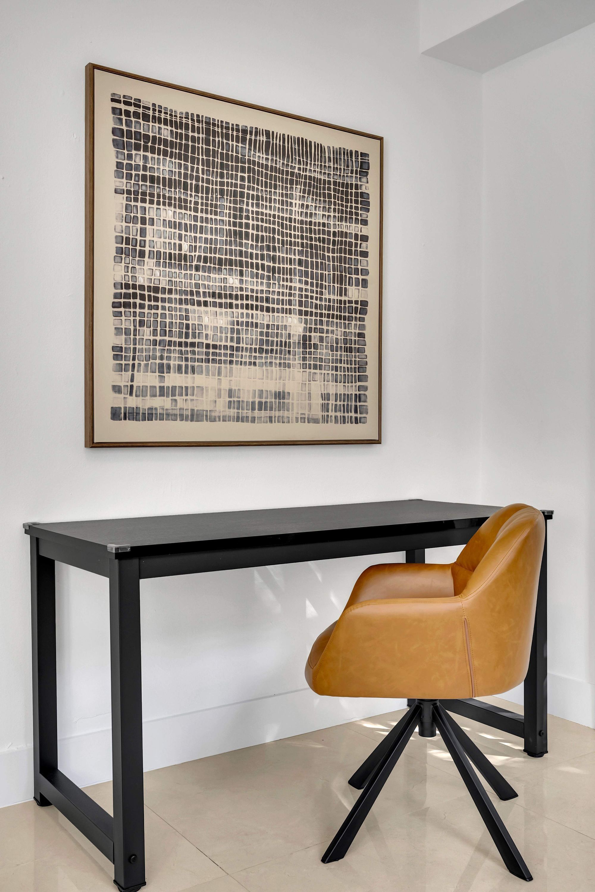 A modern office space with a black desk and a brown leather chair.