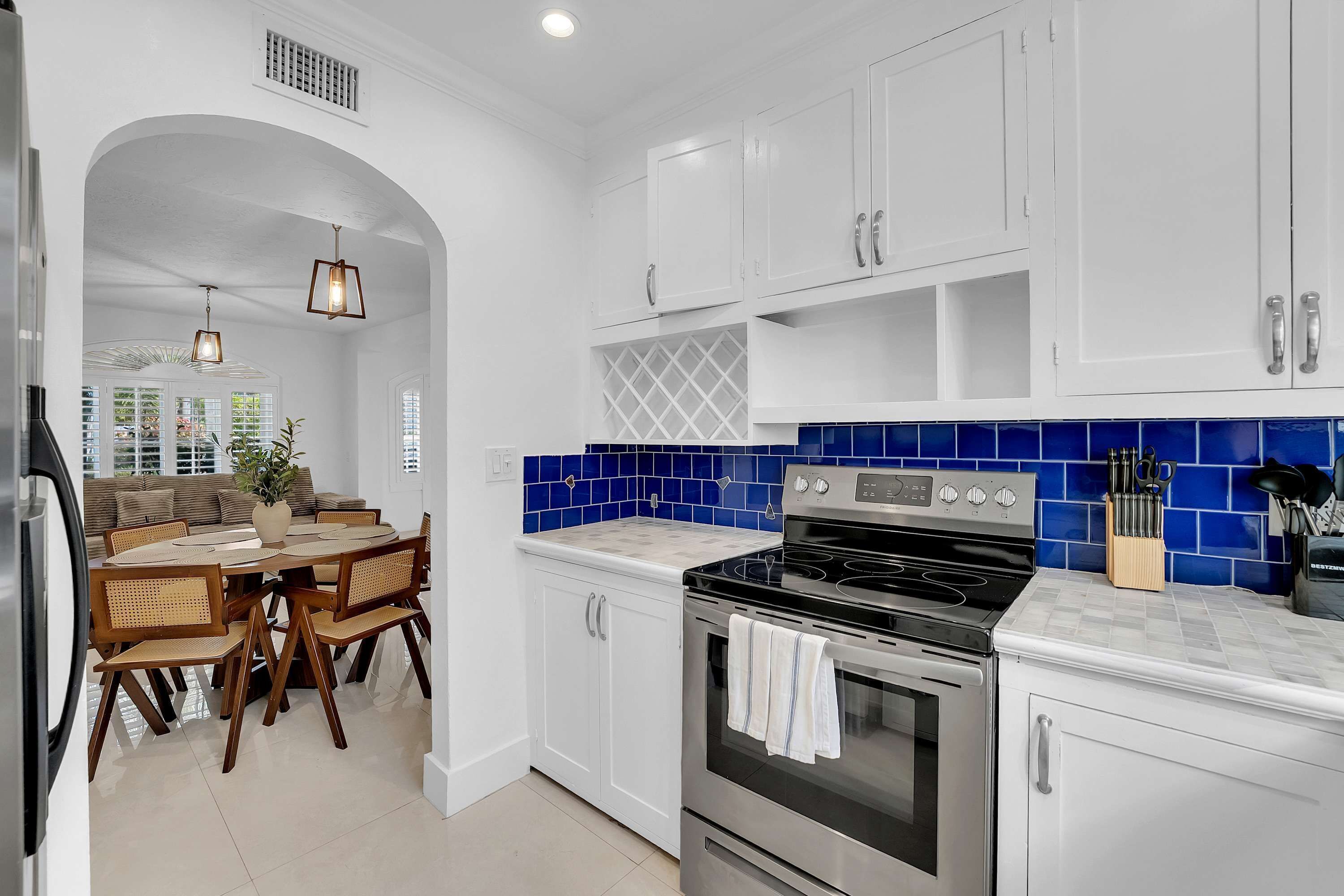 A modern kitchen with white cabinets, a black stove, and blue-tiled backsplash.