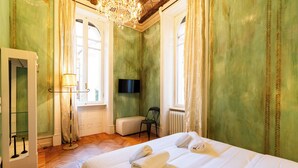 Una camera d'albergo con un letto, una sedia, una TV e una finestra.